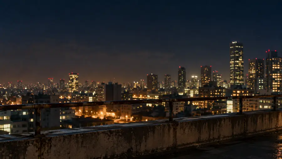City skyline at night seen from a concrete rooftop ledge
